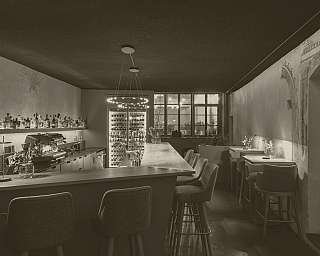 Innenansicht einer gemütlichen Bar mit Theke, Barhockern und beleuchteten Regalen