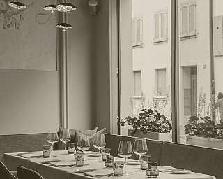 Eleganter gedeckter Esstisch mit Weingläsern und Kerzen neben großem Fenster