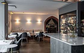 Elegantes Restaurant mit Tischen, Stühlen, Bar und Weinregal in warmem Licht